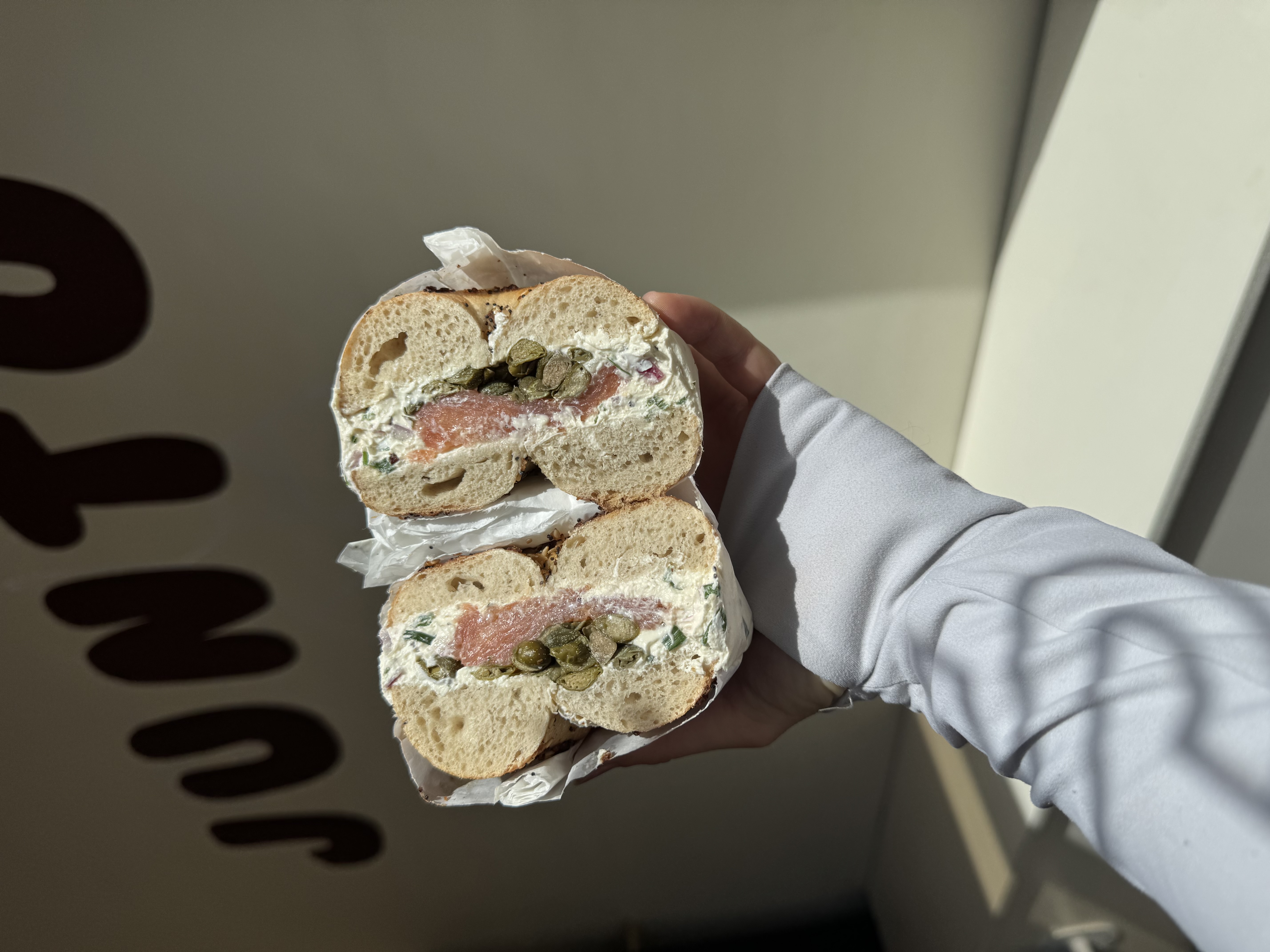 A smoked salmon, cream cheese and capers bagel held against the bear mural.