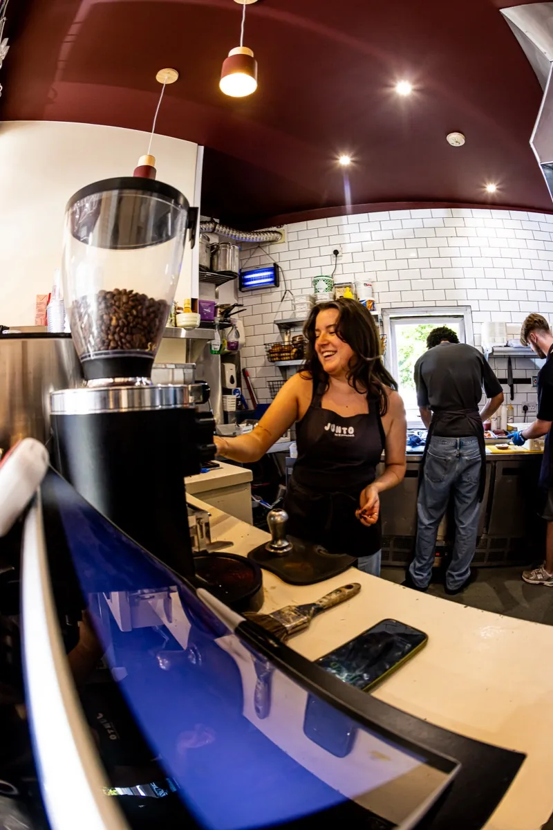 Barista smiling at the espresso grinder.